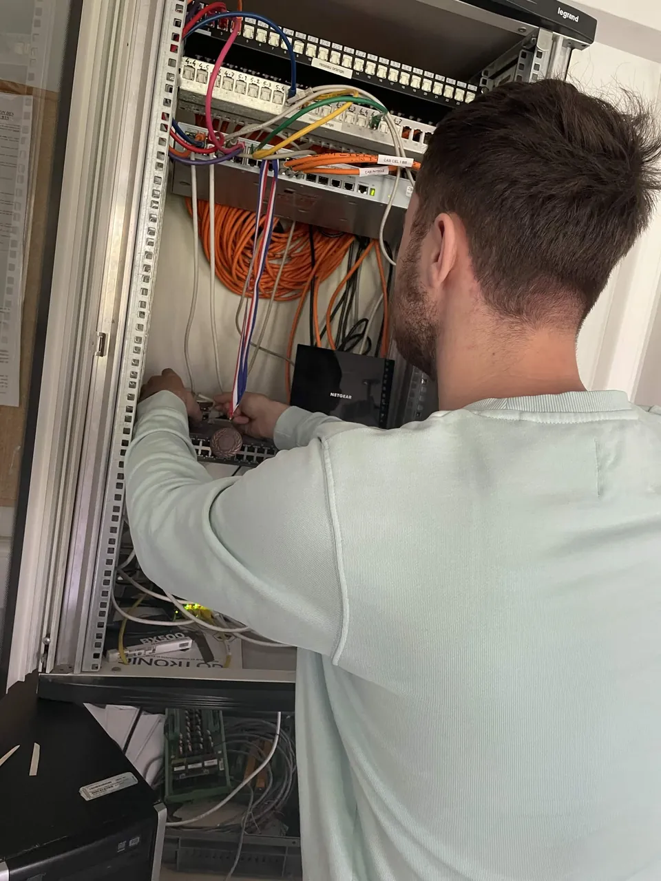 Étudiant intervenant sur la baie de brassage réseau (switch et panneaux de brassage).